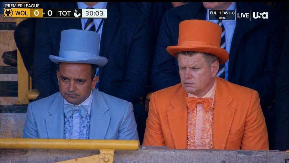 Vinai Venkatesham i baby-blå flosshatt og Johan Lange i oransje flosshatt på tribunen mens Wolves spiller 0-0 mot Tottenham